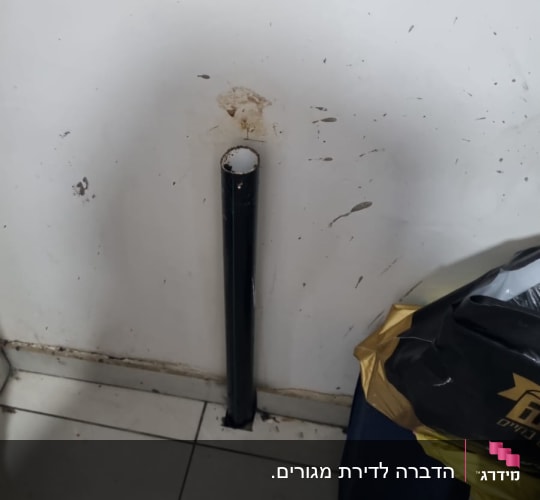 צינור שחור מחובר לקיר עם כתמים